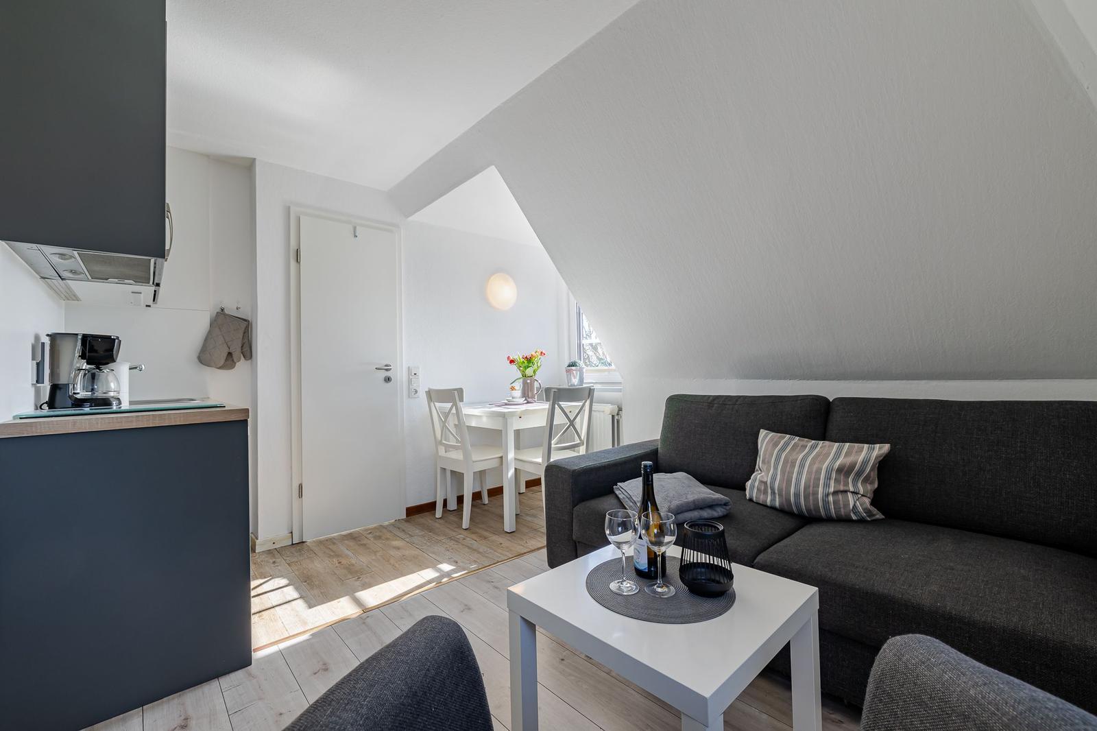 Wohnzimmer mit Sofa, Esstisch und Küche unter Dachschrägen