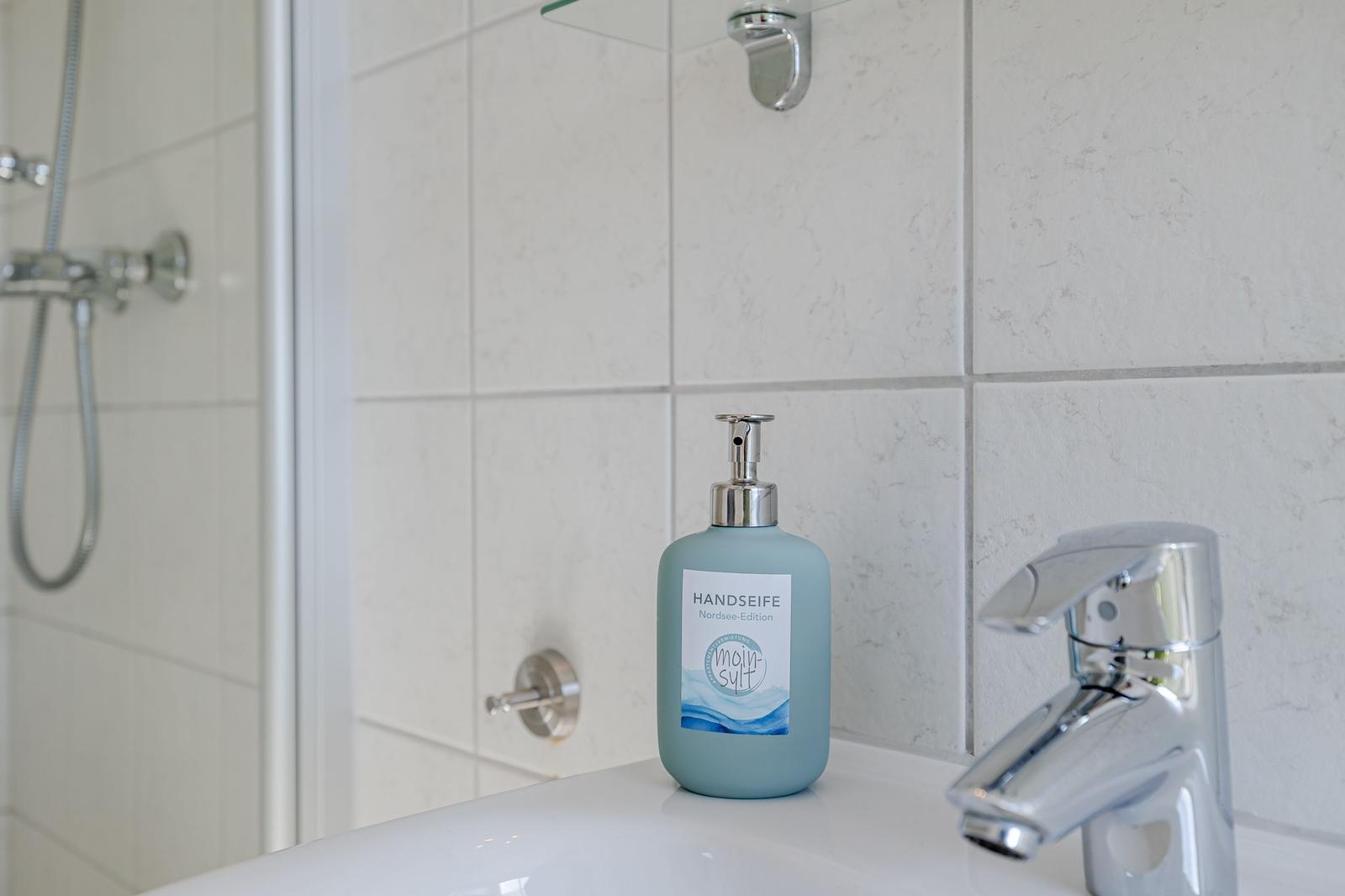 Waschbecken mit Seife und Dusche im Badezimmer