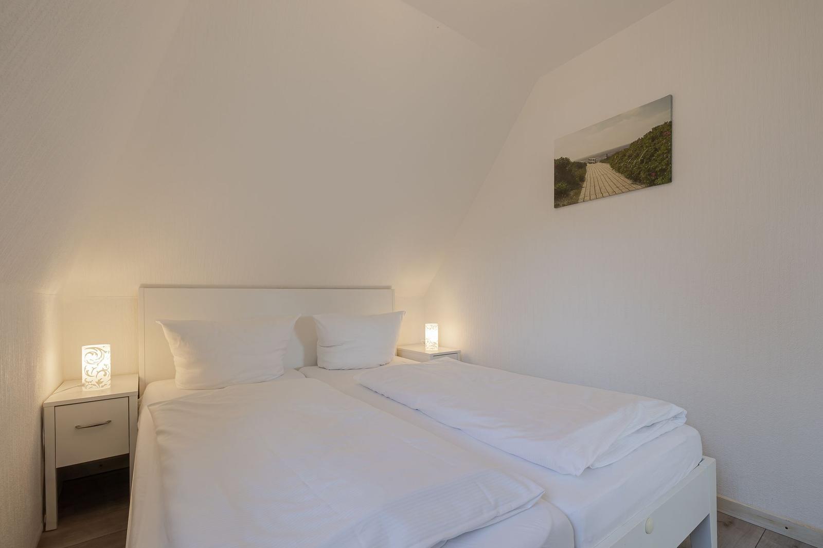 Schlafzimmer mit Doppelbett, zwei Nachttischen und Wandbild.