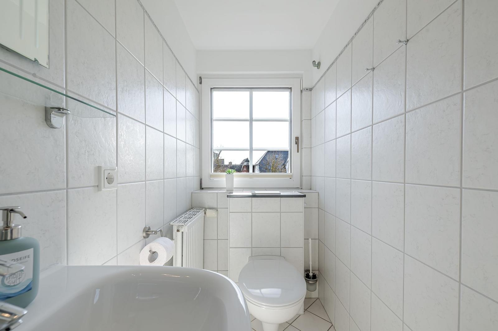 Badezimmer mit Toilette, Waschbecken und Fenster