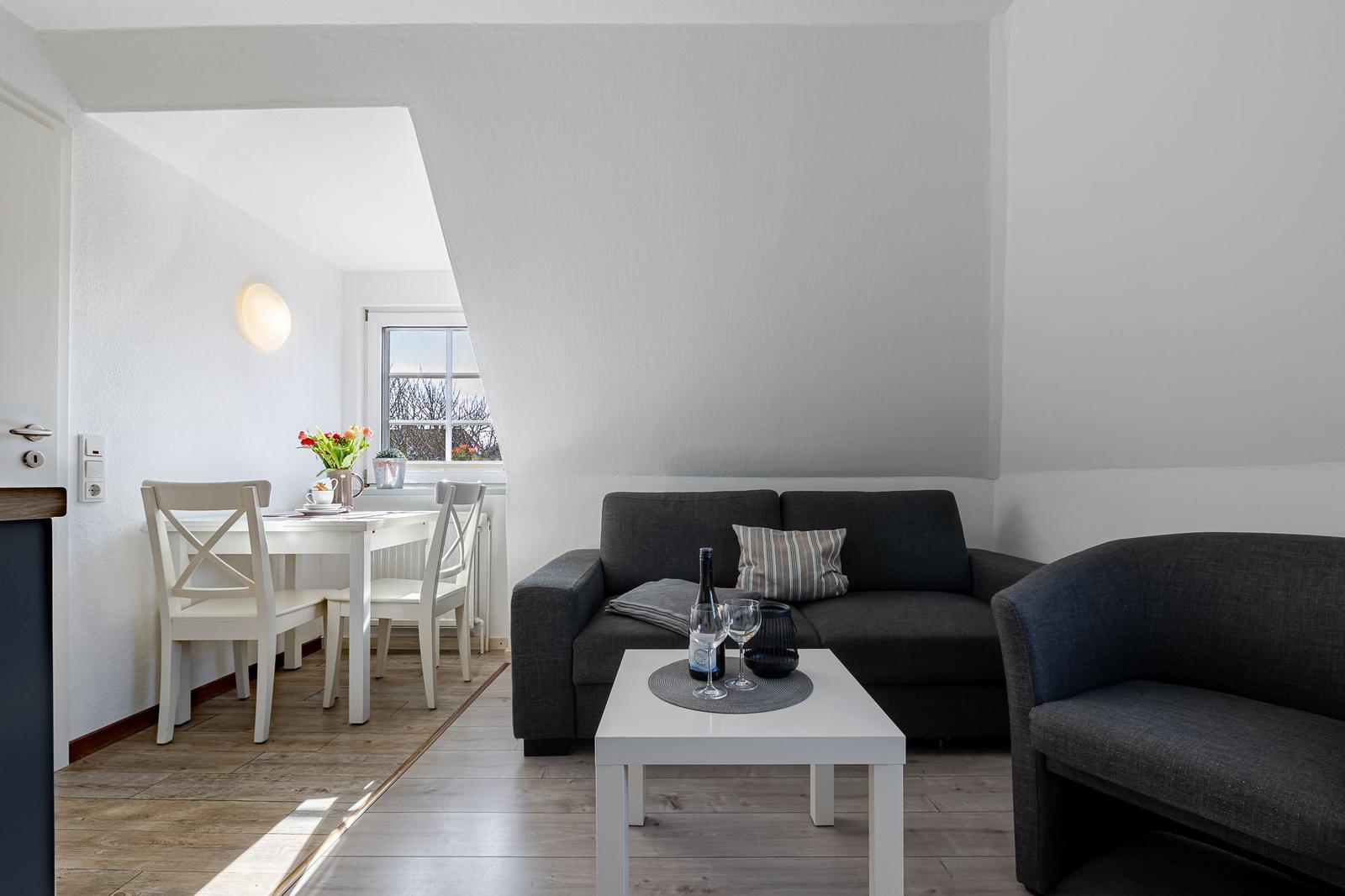 Wohnzimmer mit Sofa, Couch und Esstisch. Fenster mit Blick nach draußen.