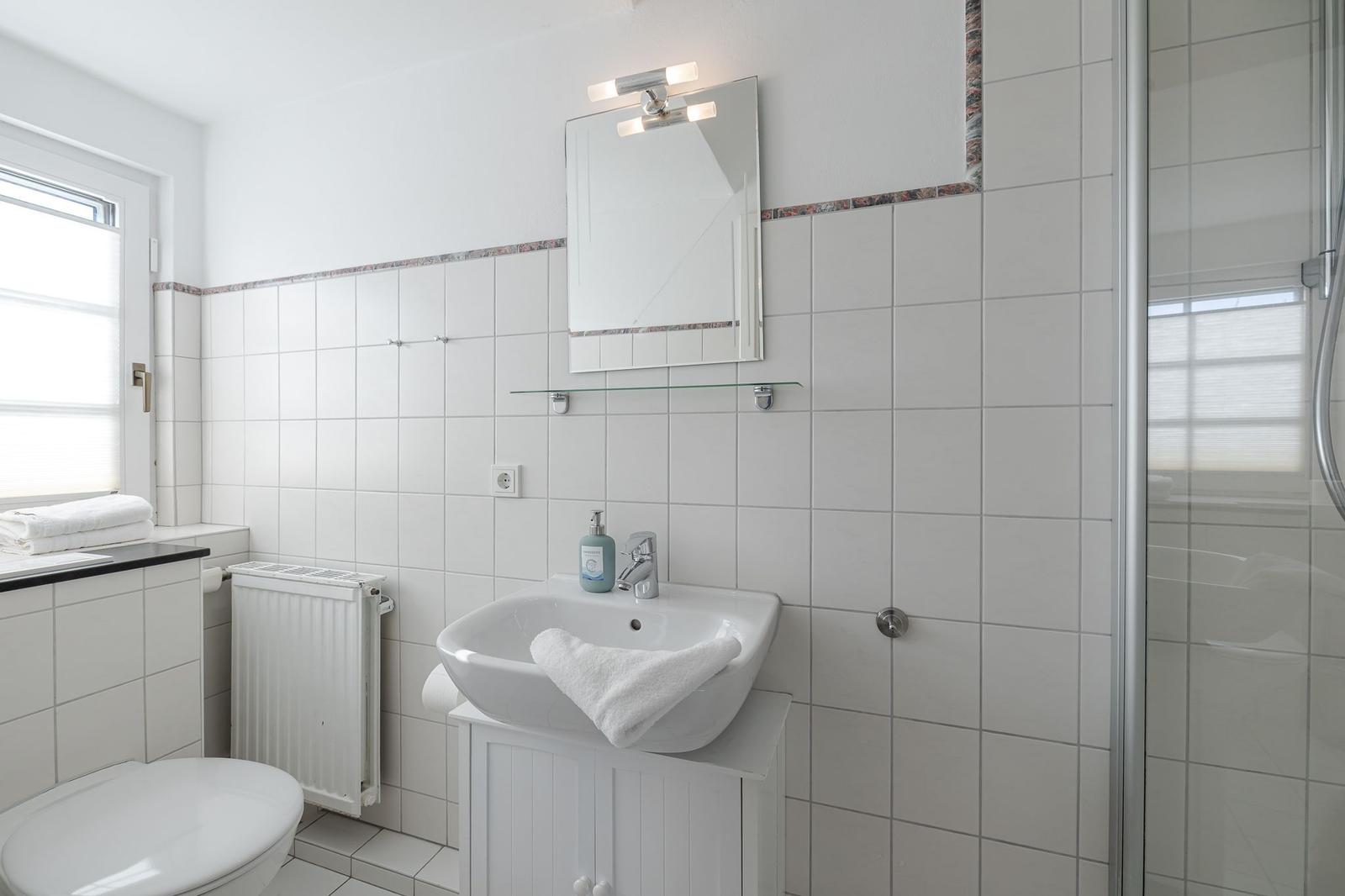Badezimmer mit Dusche, Waschbecken und Toilette.