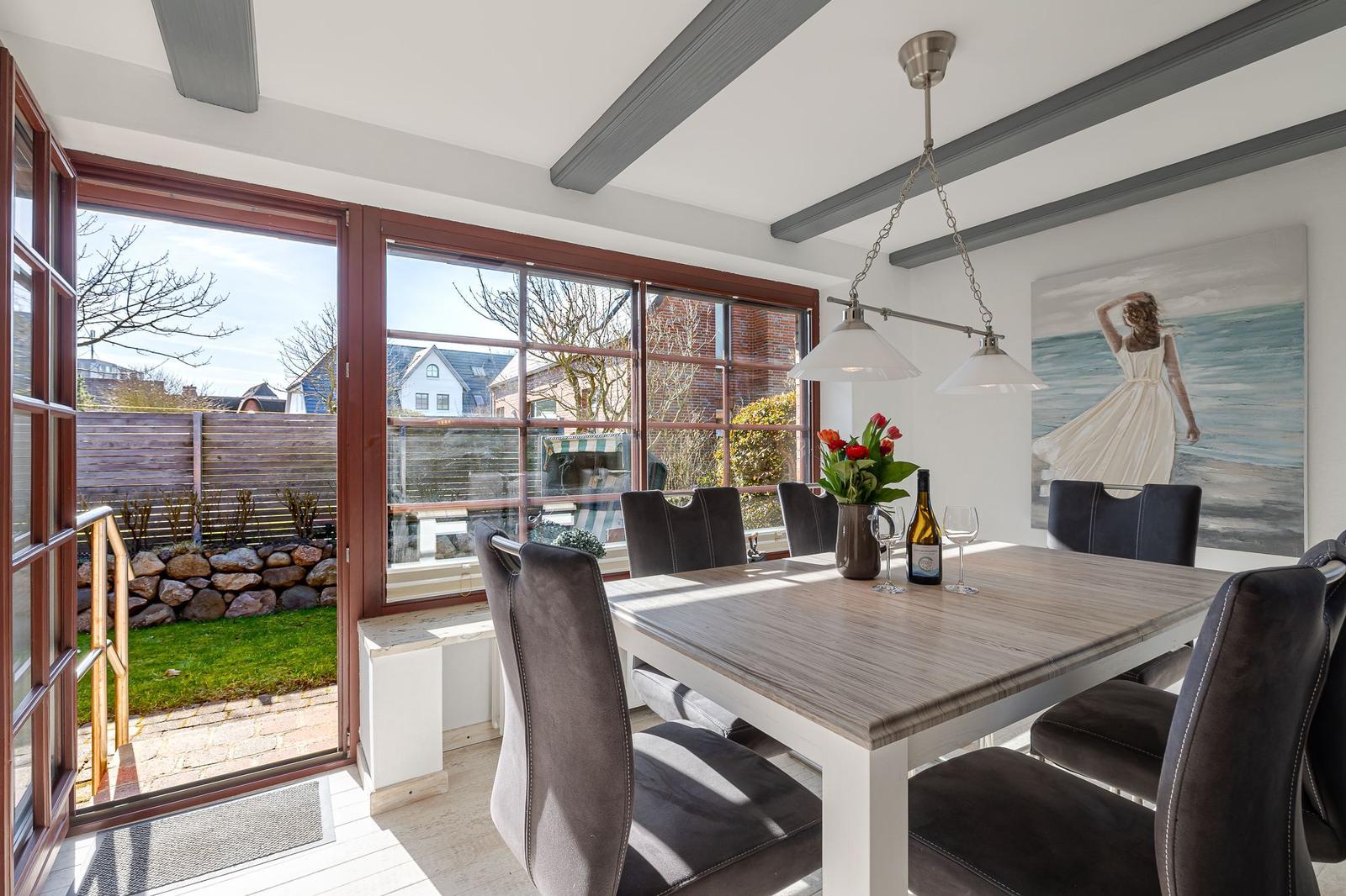 Esstisch mit Stühlen, Fenster zur Terrasse und Wandbild.