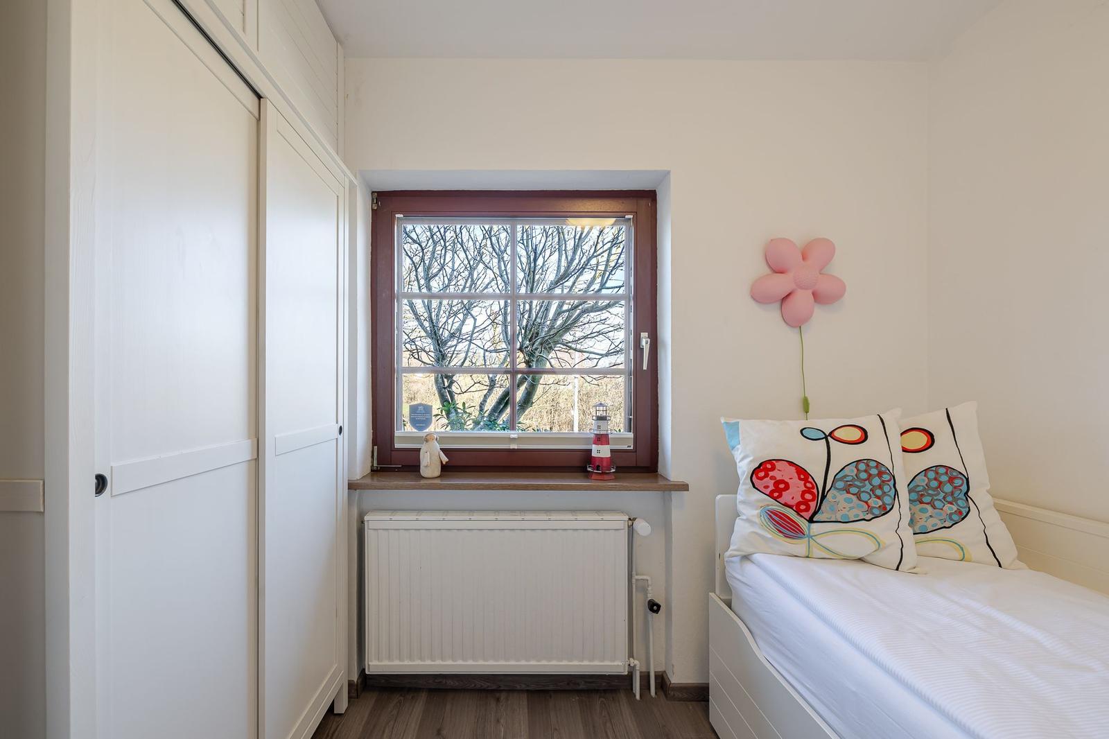 Schlafzimmer mit Bett, Fenster und Kleiderschrank.