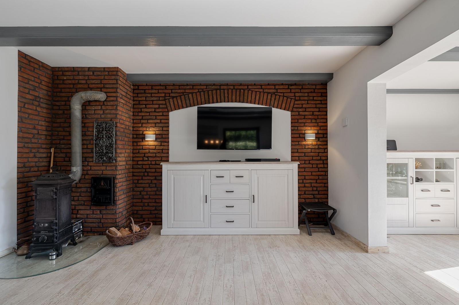 Raum mit Backsteinwand, Fernseher, Schrank und Kaminofen.