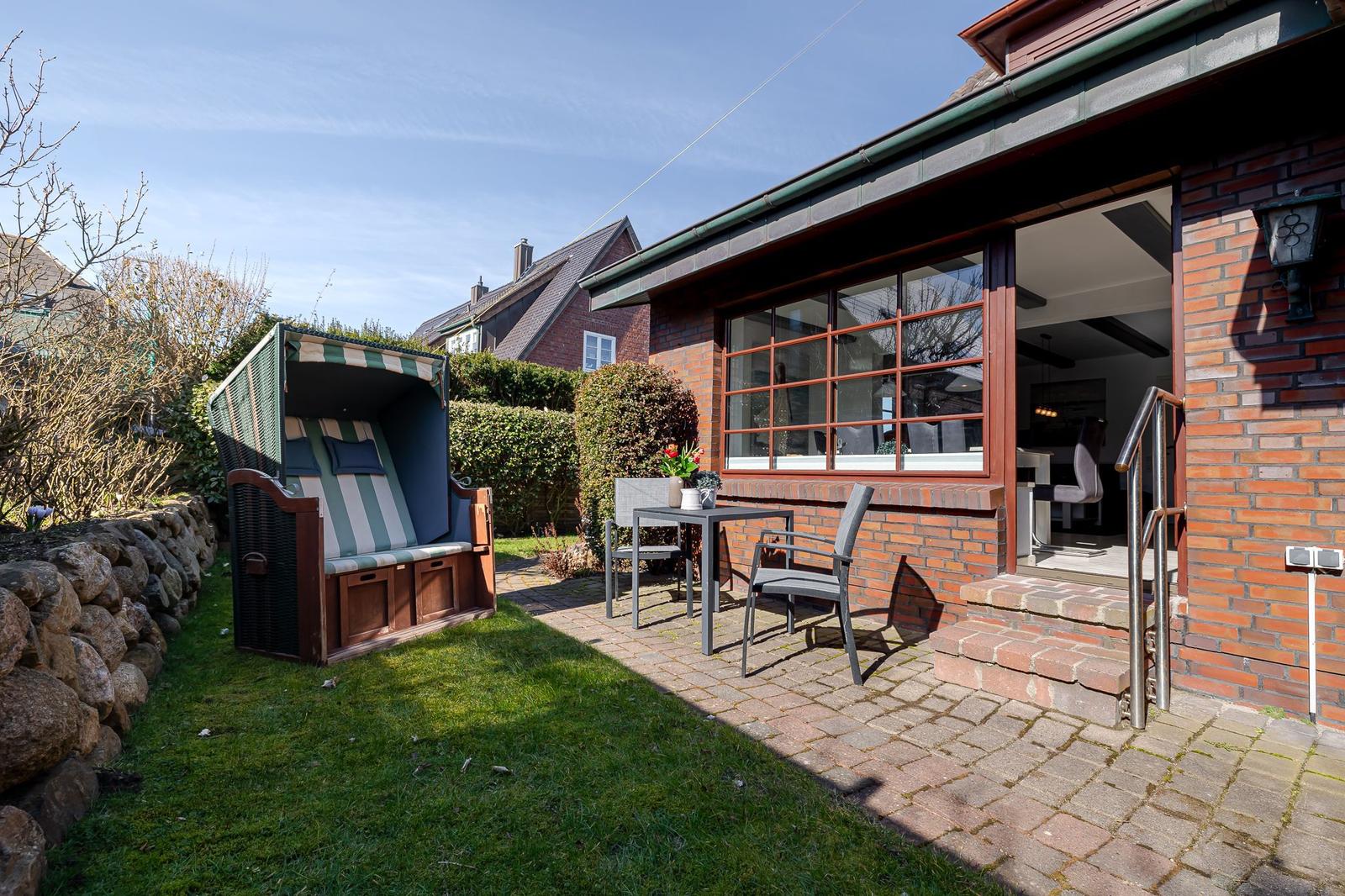 Rotes Backsteinhaus mit Terrasse, Strandkorb und Garten.