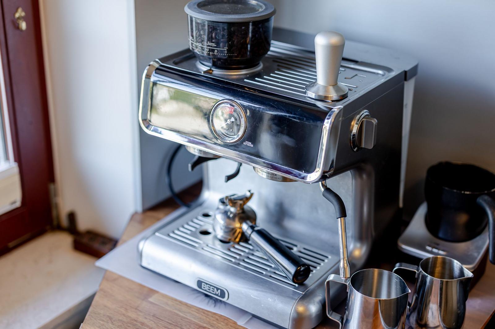Espresso-Kaffeemaschine mit Mahlwerk und Milchkanister auf Holztisch