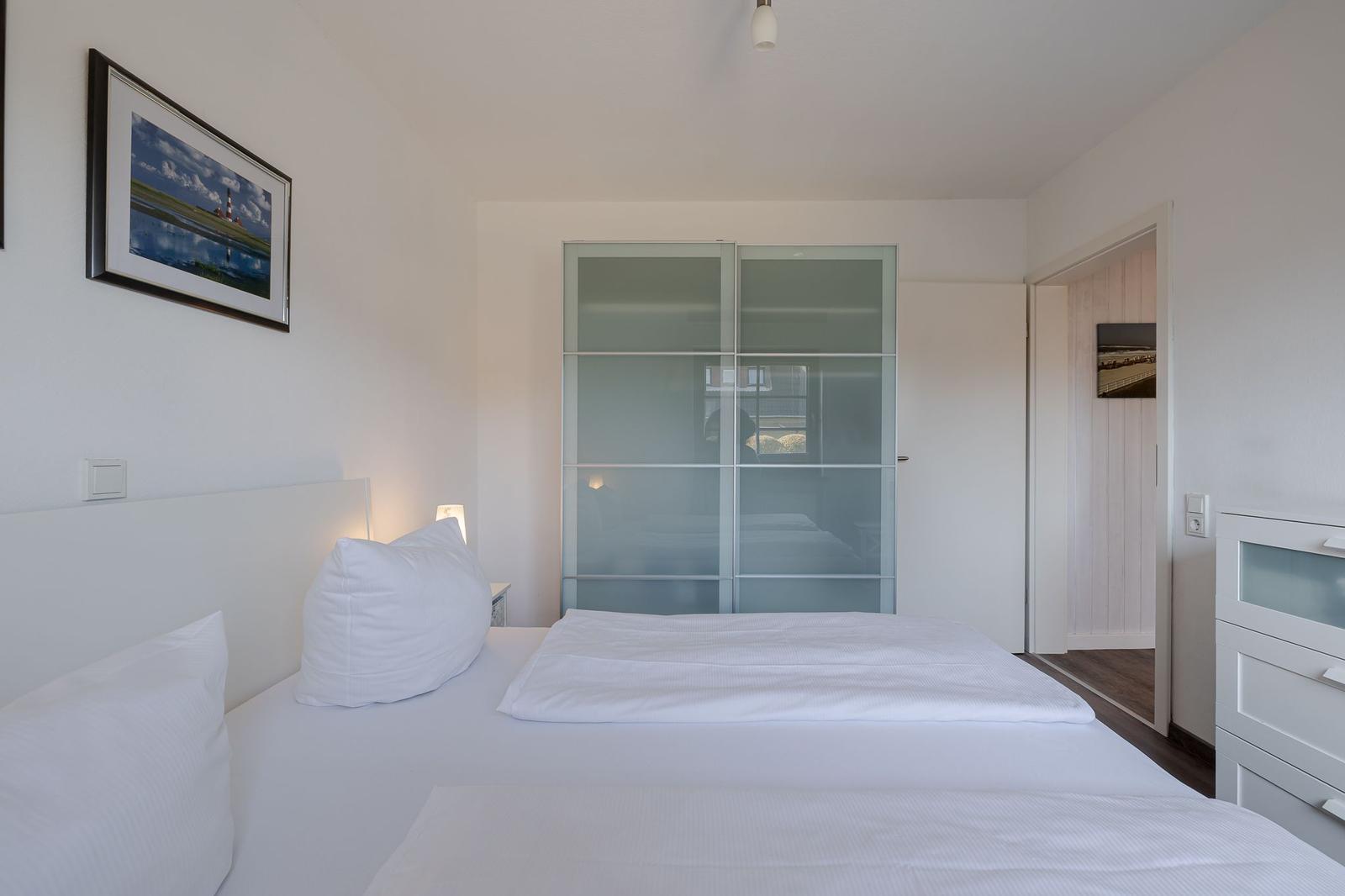 Schlafzimmer mit Doppelbett, Schrank und Wandbild.