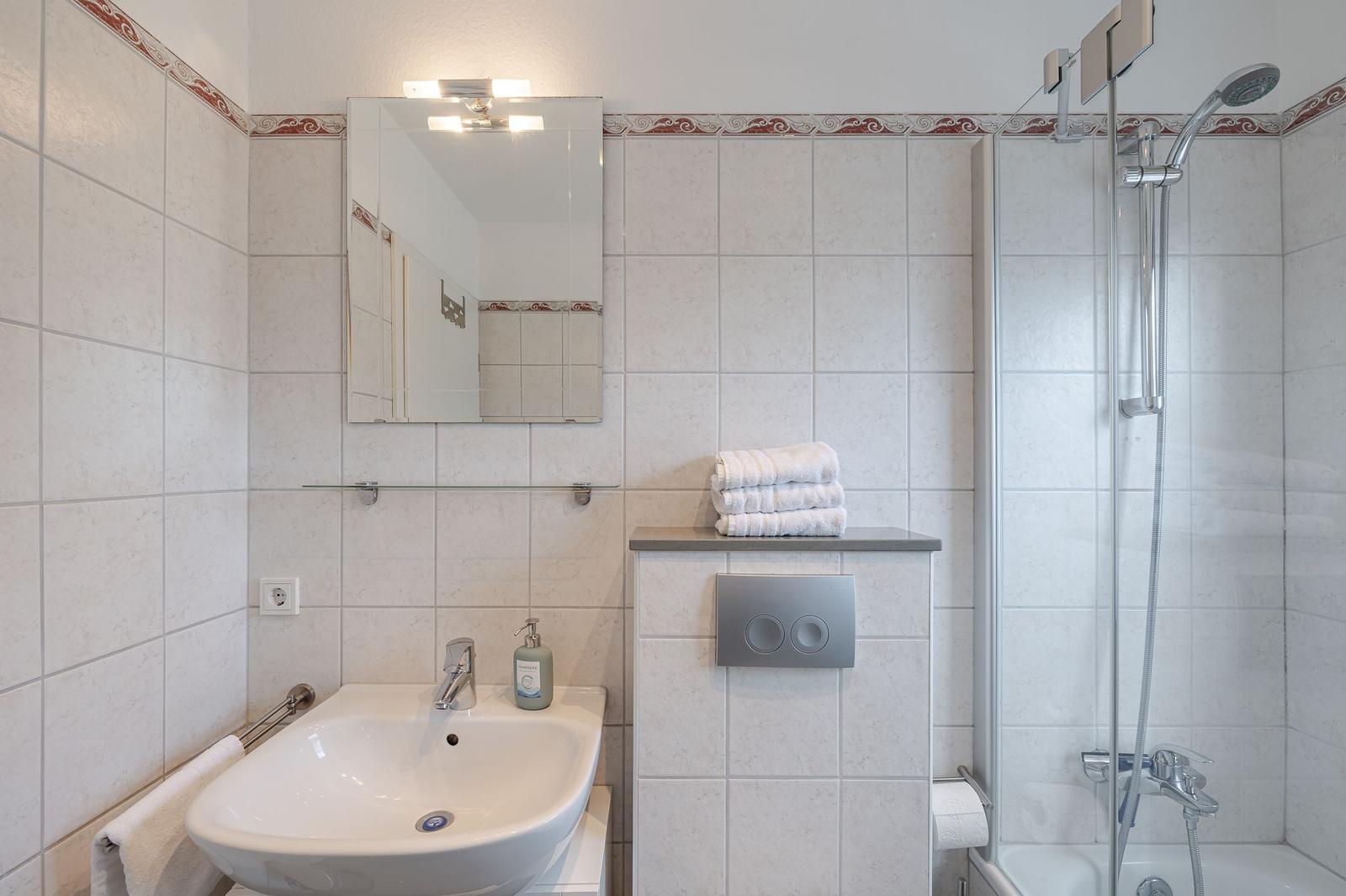 Badezimmer mit Dusche, Waschbecken und Spiegel