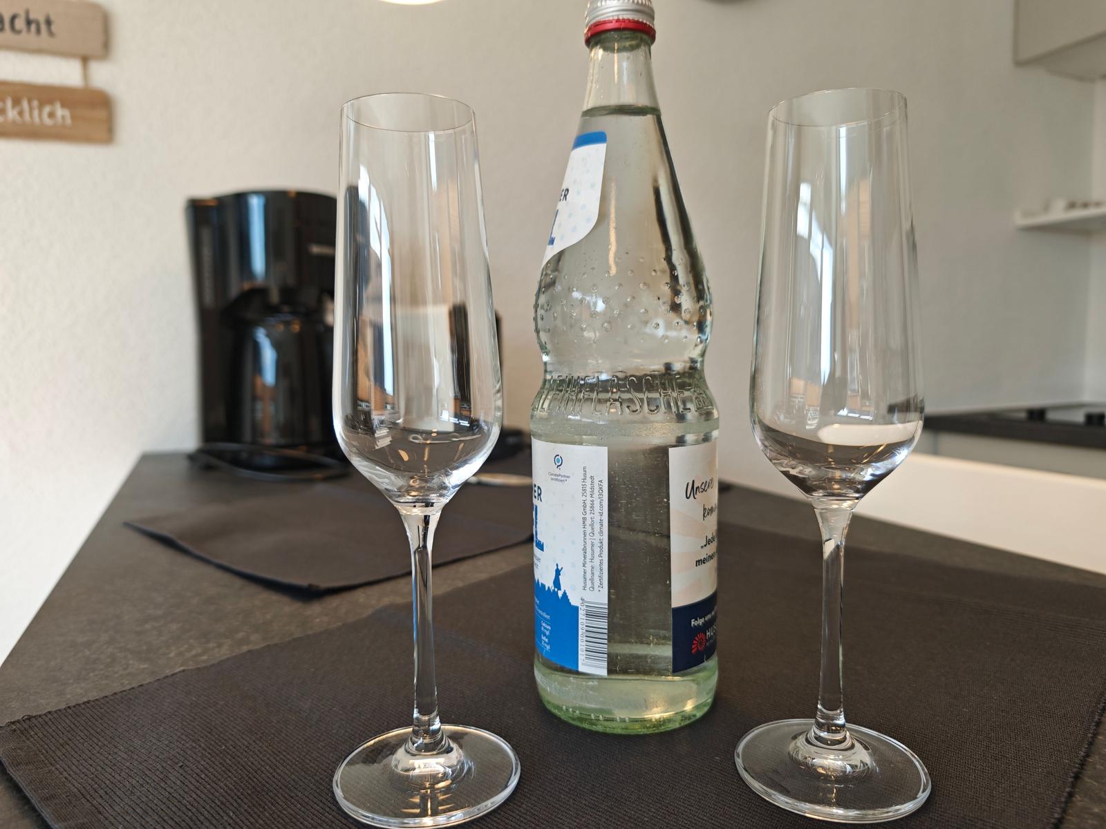 Zwei Flöten und eine Flasche Mineralwasser auf Tisch