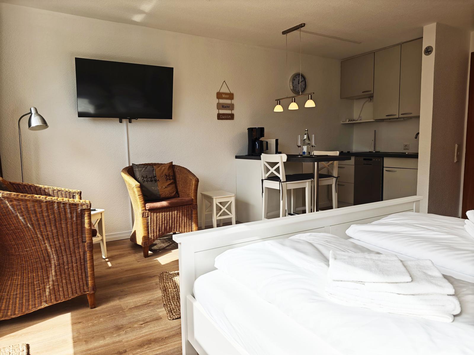 Schlafzimmer mit Bett, Sessel und Küchenbereich.