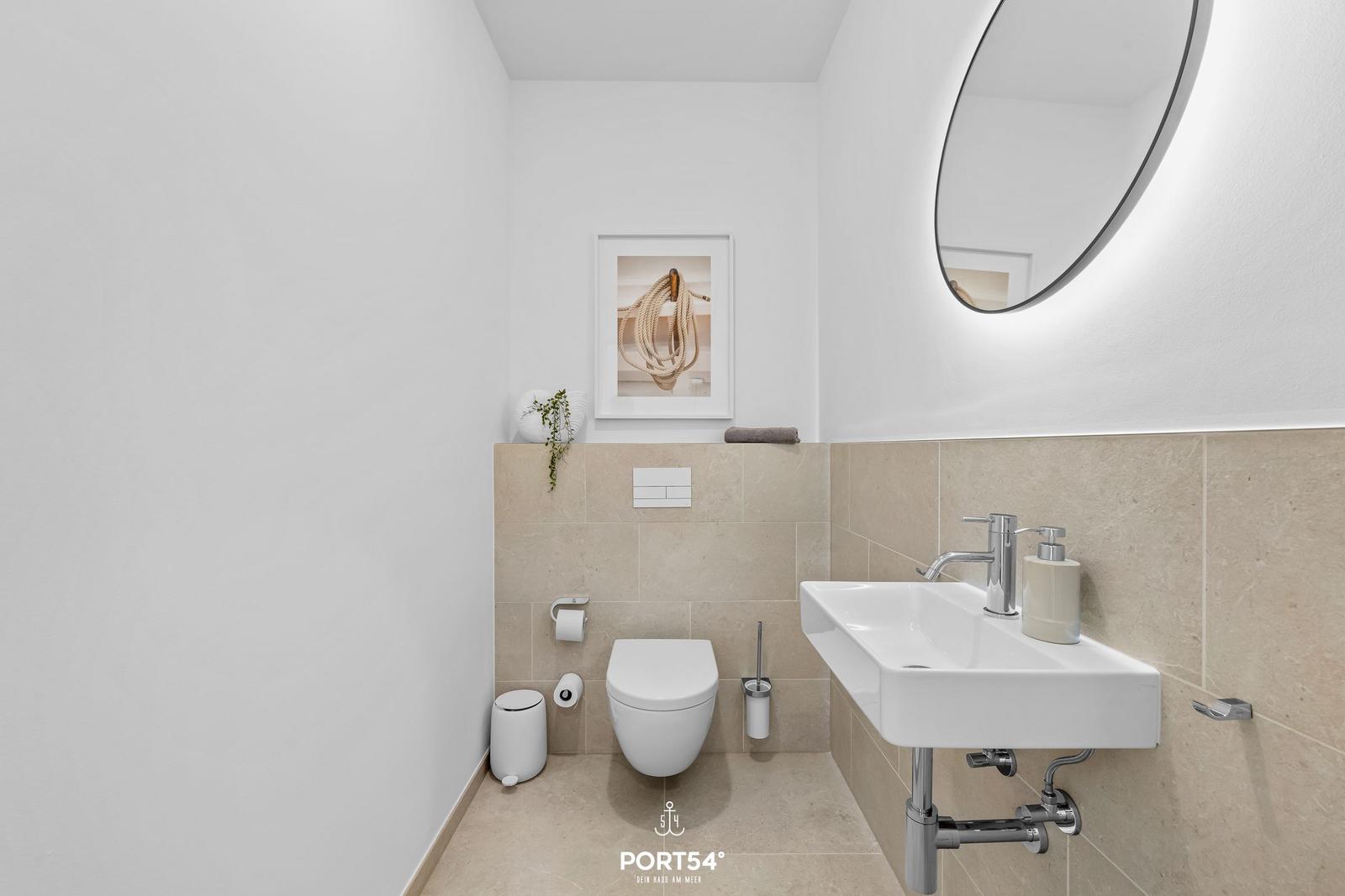 Badezimmer mit Waschbecken, Toilette und runden Spiegel