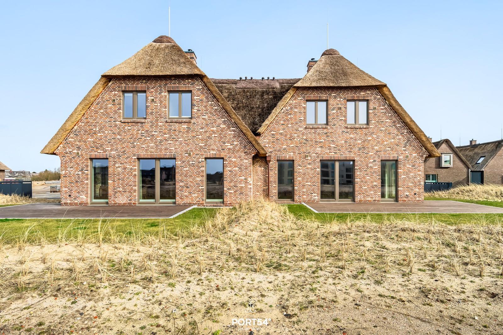 Zweistöckiges Haus mit strohgedeckten Dächern und großen Fenstern