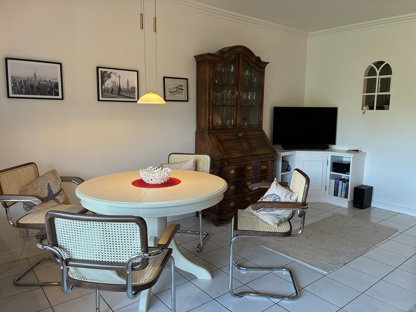 Rundtisch mit Stühlen, Schrank und Fernseher im Wohnzimmer