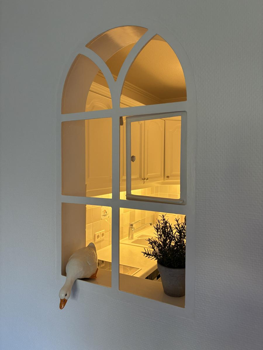 Blick durch ein Fenster auf eine Badewanne und eine Pflanze.