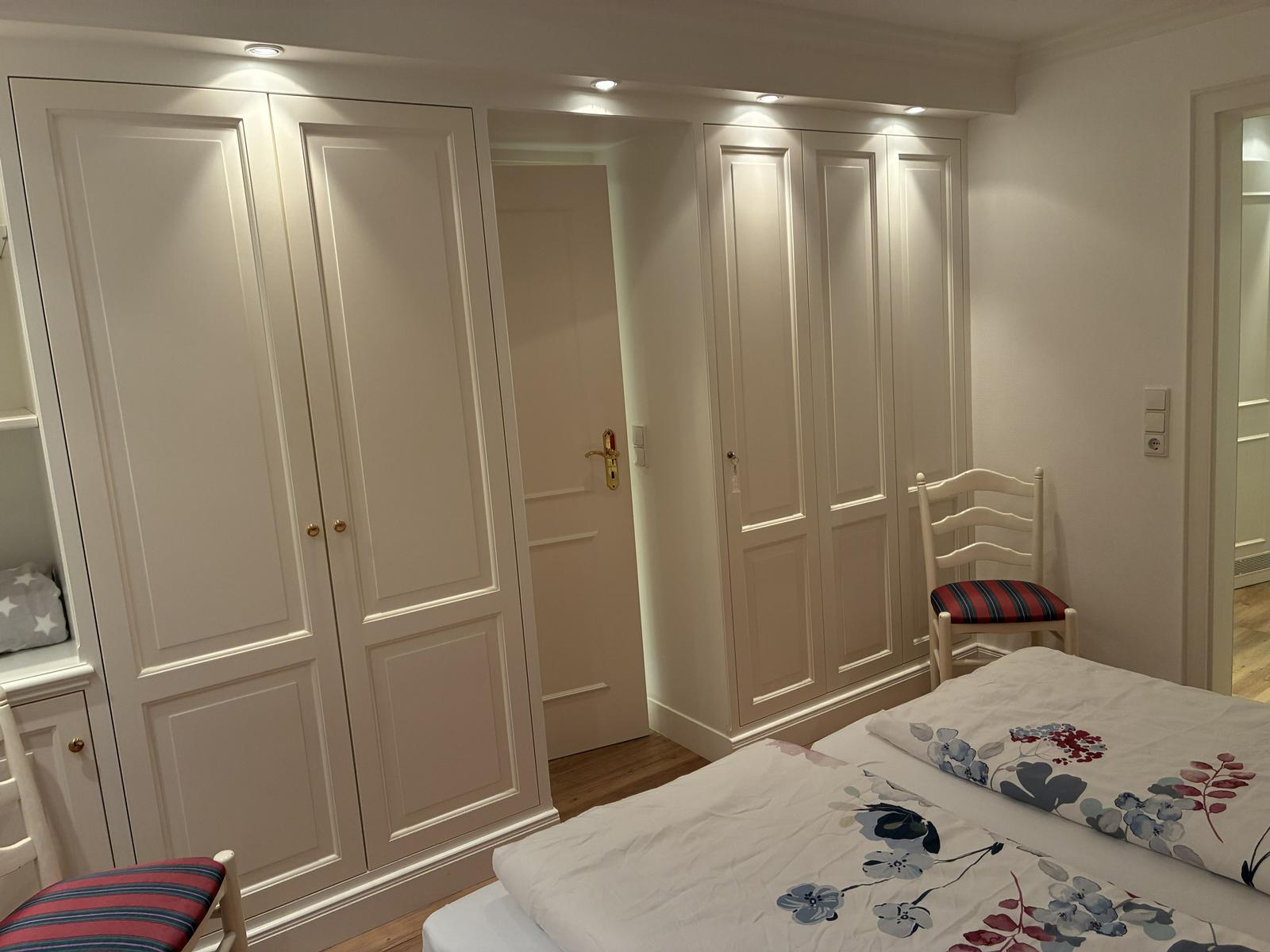 Schlafzimmer mit Bett, Kleiderschränken und Stuhl.