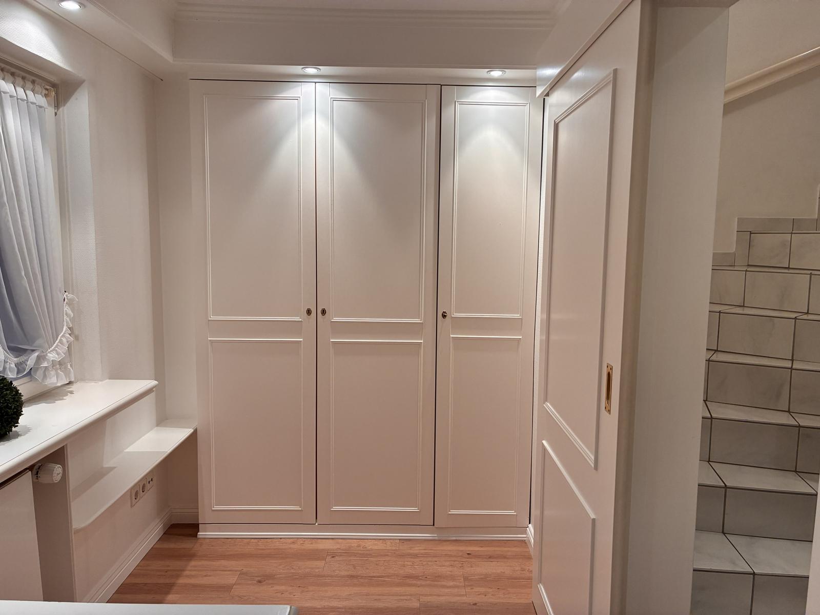 Schlafzimmer mit Kleiderschrank, Fenster und Holzboden. Treppe führt nach oben.