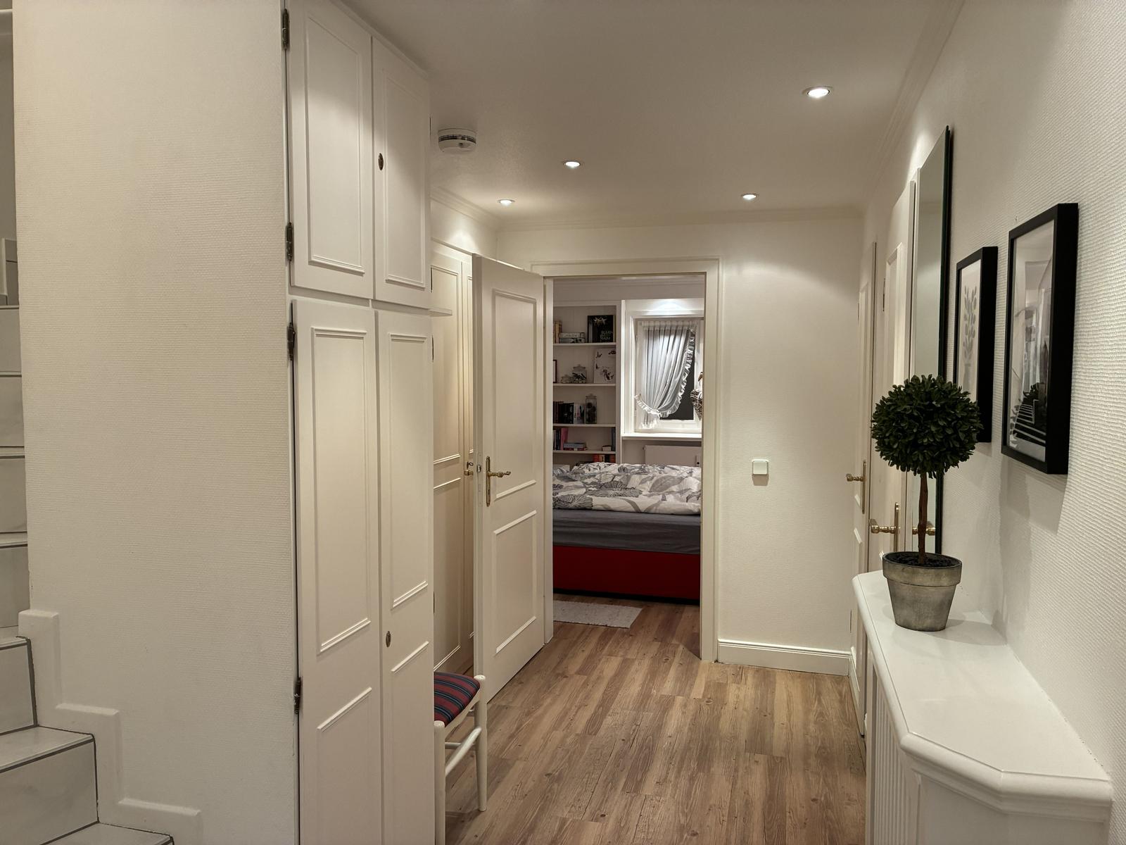 Flur mit Kleiderschrank, Zimmer mit Bett und Bücherregal