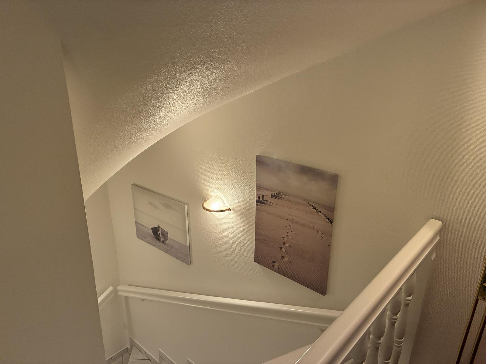 Treppenhaus mit weißen Geländern und Wandbildern an der Wand.