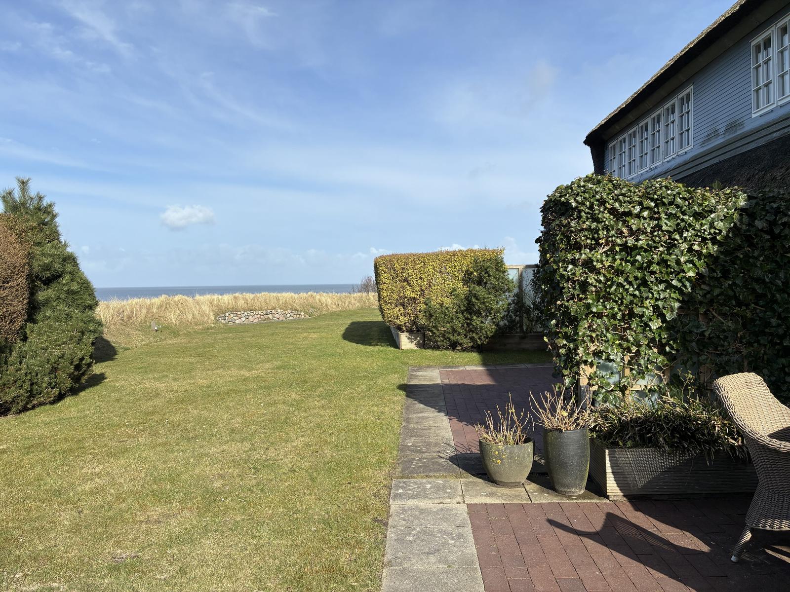 Garten mit Blick auf das Meer, Terrasse und grüne Pflanzen.