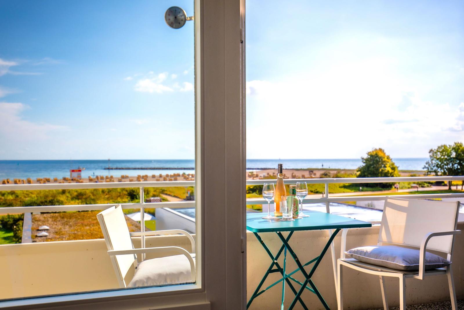 Balcony with table and chairs overlooking the sea and beach.