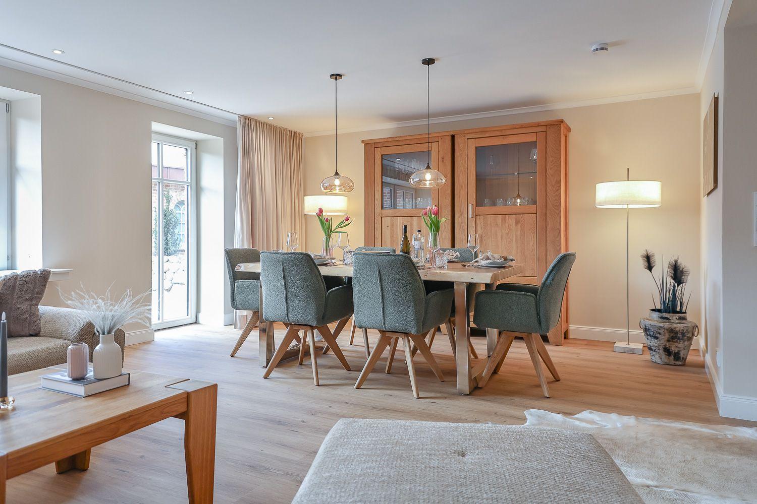 Esszimmer mit Holztisch, Stühlen und Sideboard. Lichtdurchfluteter Raum mit Holzboden.