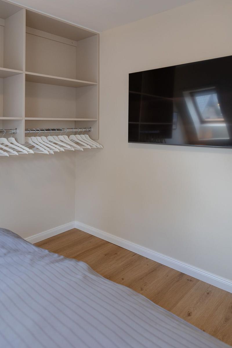 Schlafzimmer mit Kleiderschrank und Wandfernseher