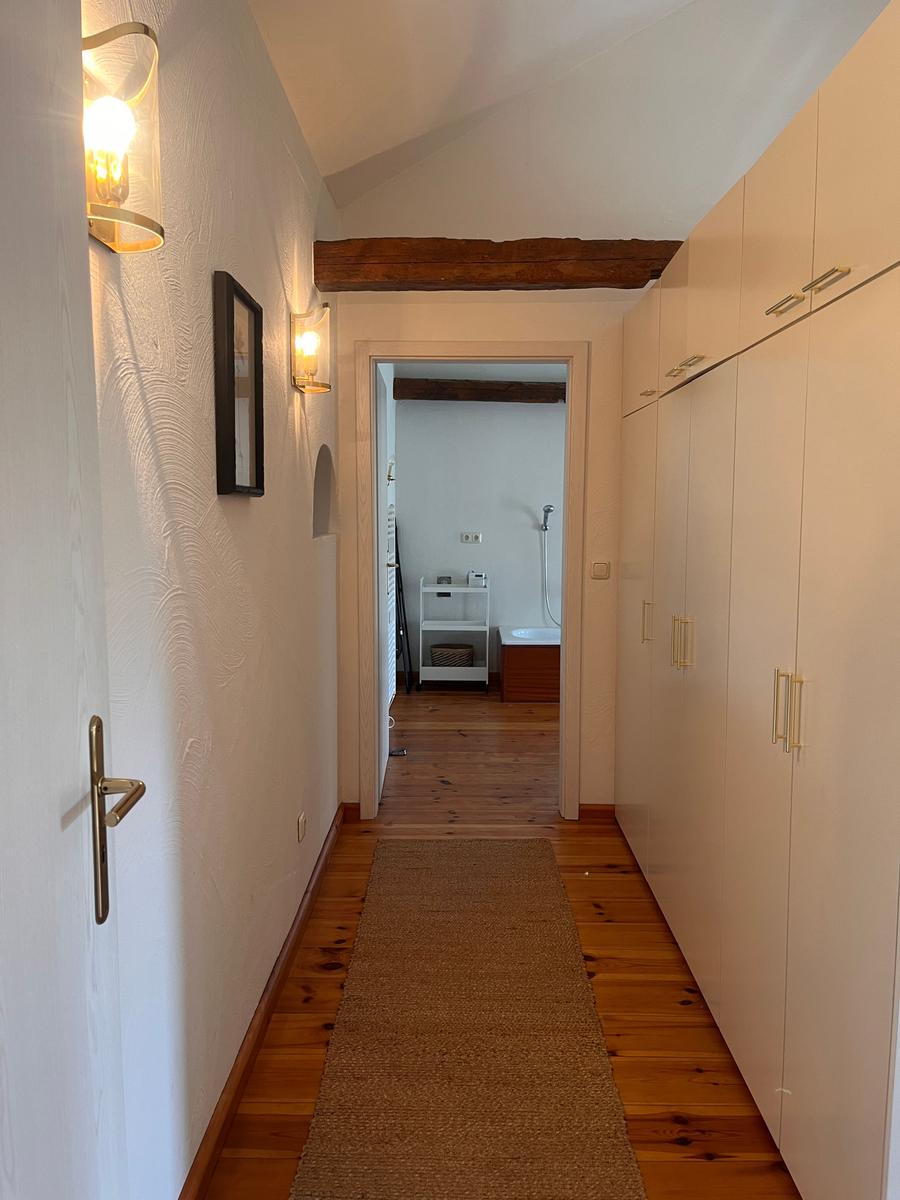 Flur mit Holzboden, Garderobe und Blick in Bad