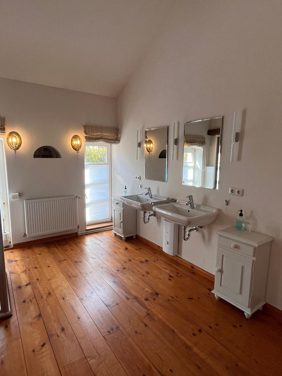 Badezimmer mit zwei Waschbecken, Spiegeln und Holzboden