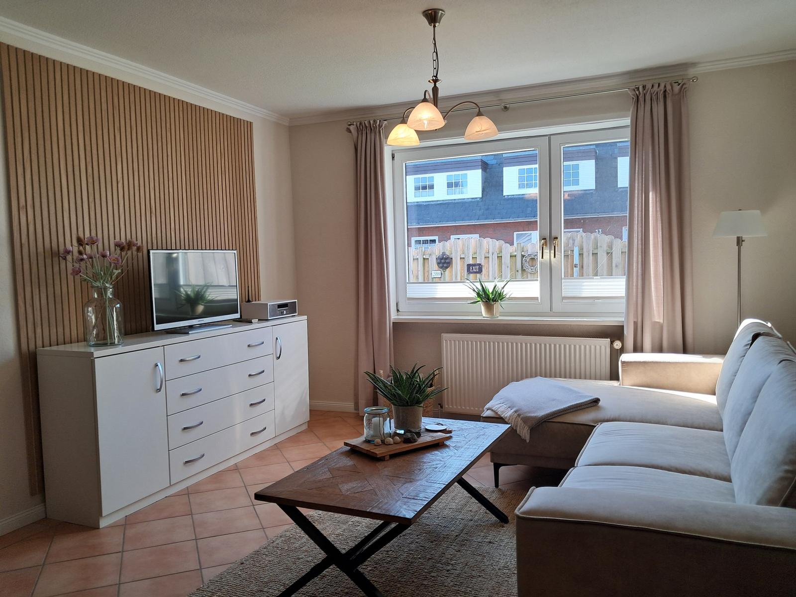 Wohnzimmer mit Sofa, Couchtisch und Fernseher an Holzwand