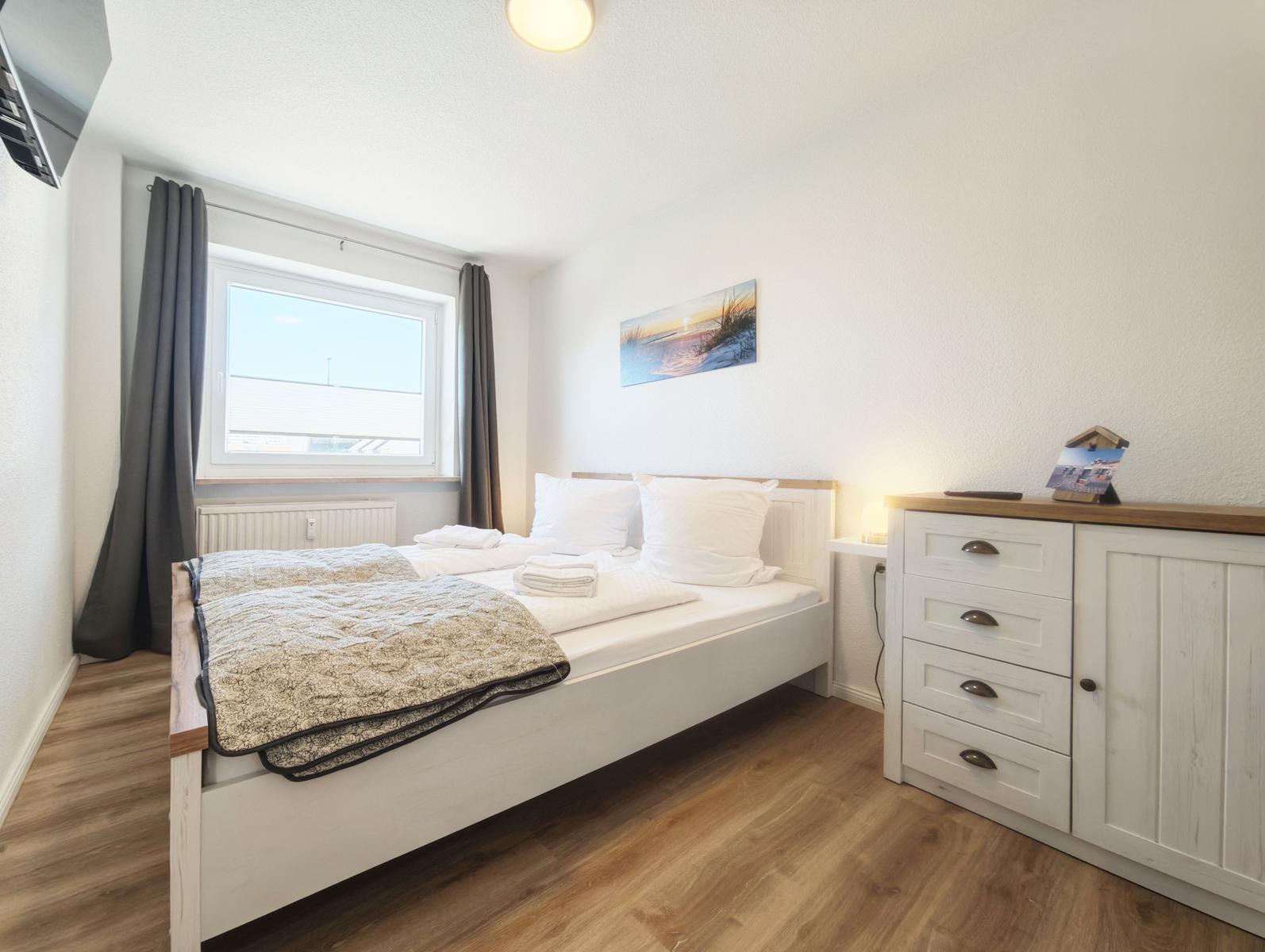 Schlafzimmer mit Bett, Schrank und Fenster