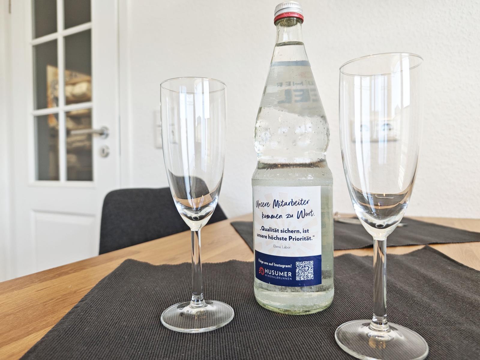 Auf dem Tisch stehen zwei Gläser und eine Flasche Mineralwasser.