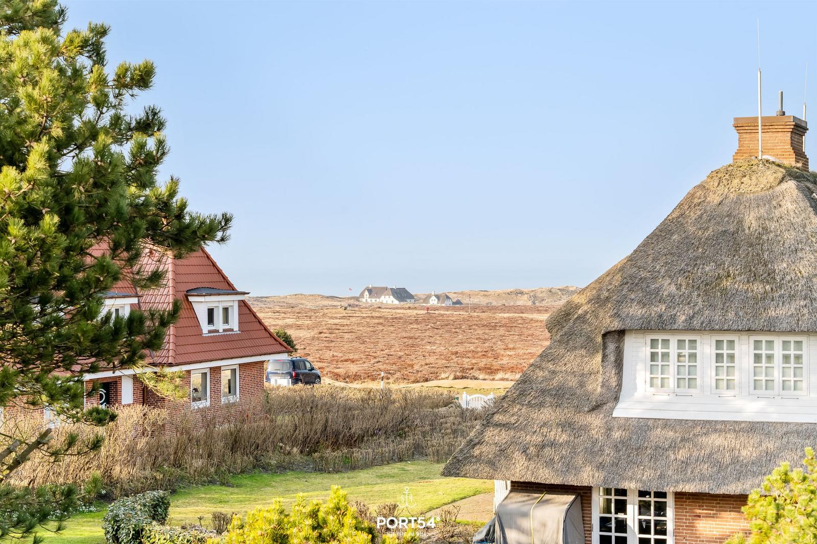 Haus mit Strohdach und rotem Dach, Blick auf Felder und Ferienhäuser