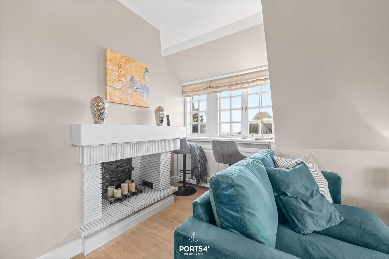 Ein Wohnzimmer mit Kamin, blauem Sofa und Fenster mit Blick.