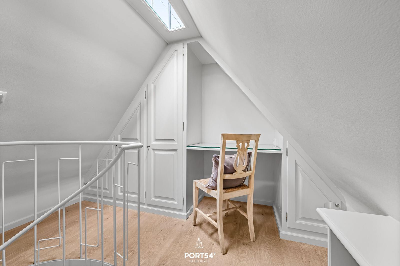 Dachgeschosszimmer mit Schreibtisch, Stuhl und Dachfenster.