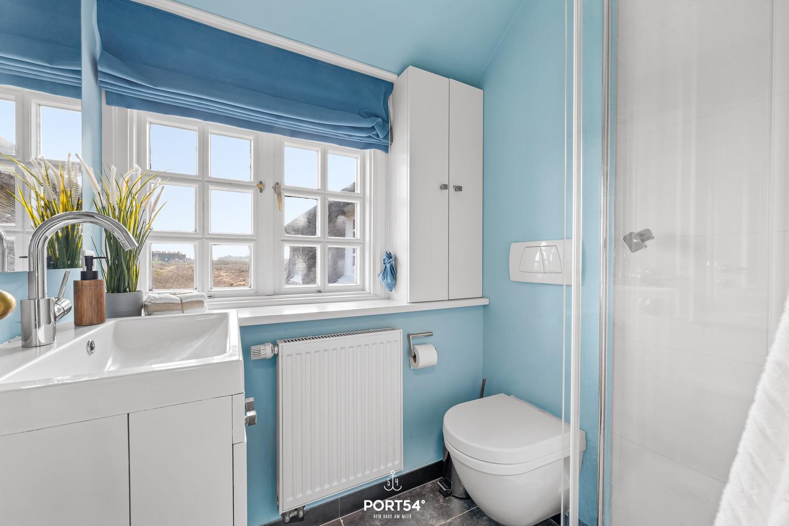 Badezimmer mit blauen Wänden, Fenster, Waschbecken und Dusche.