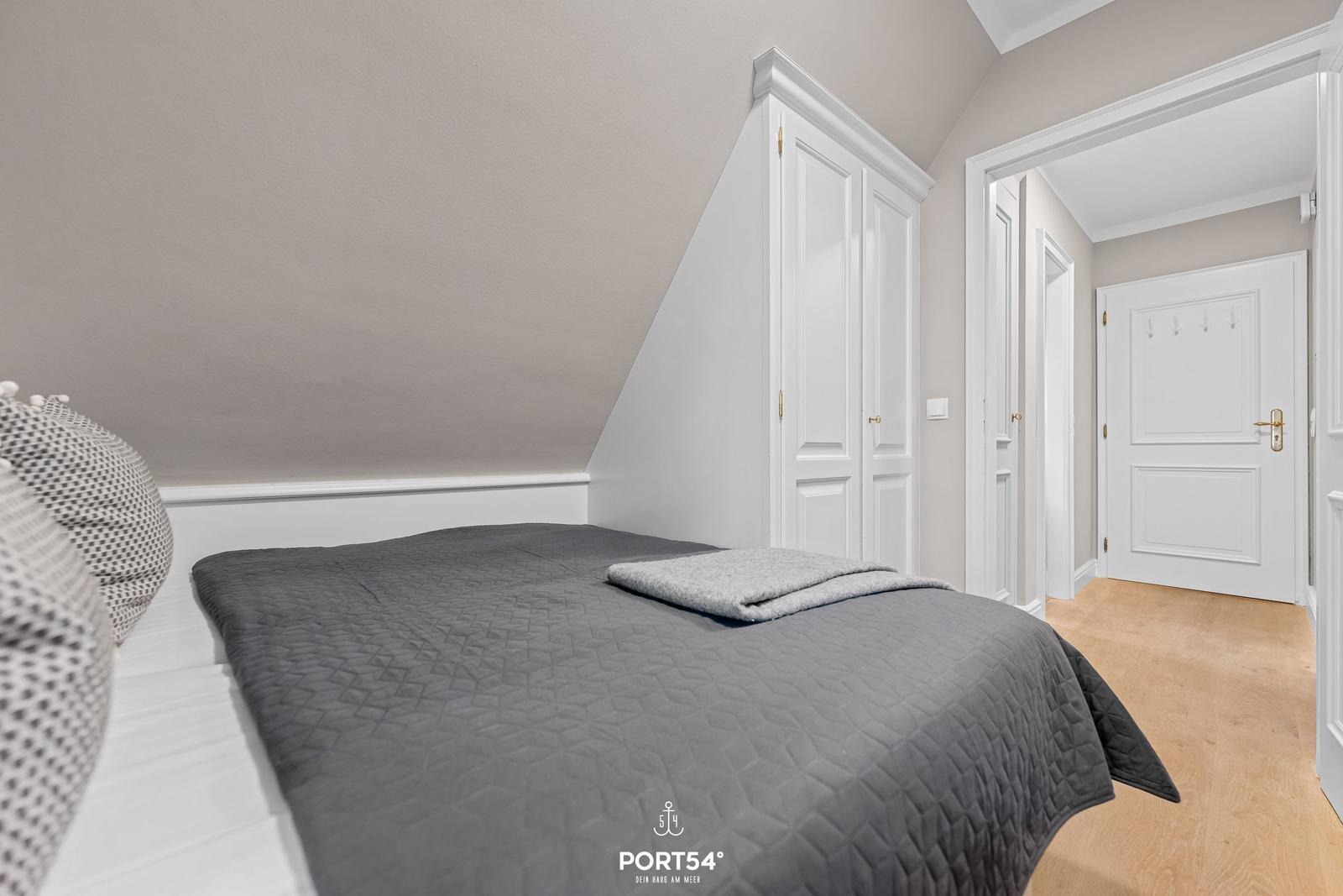Schlafzimmer mit Dachschrägen, Bett und Kleiderschrank.