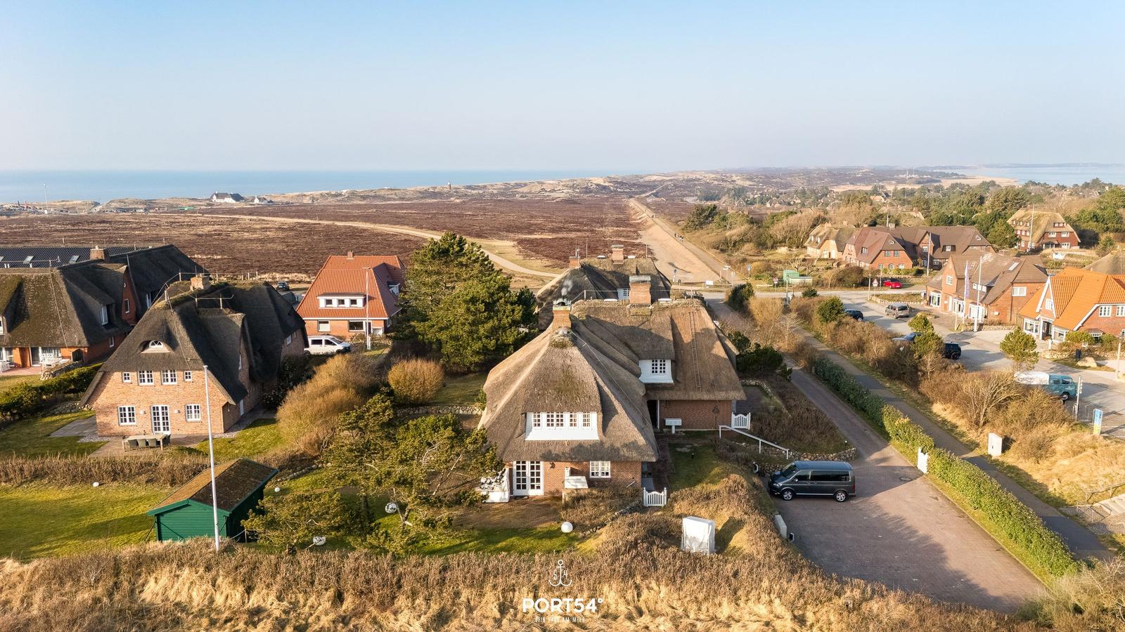 Dorf mit strohgedeckten Häusern und Blick auf die Nordsee.