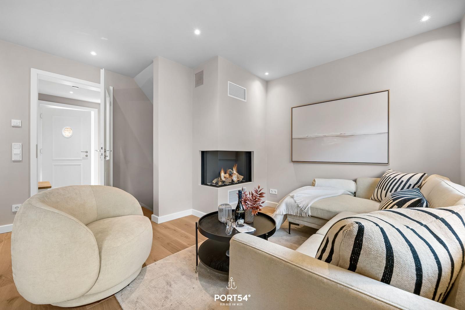 Wohnzimmer mit Sofa, Sessel und Kamin