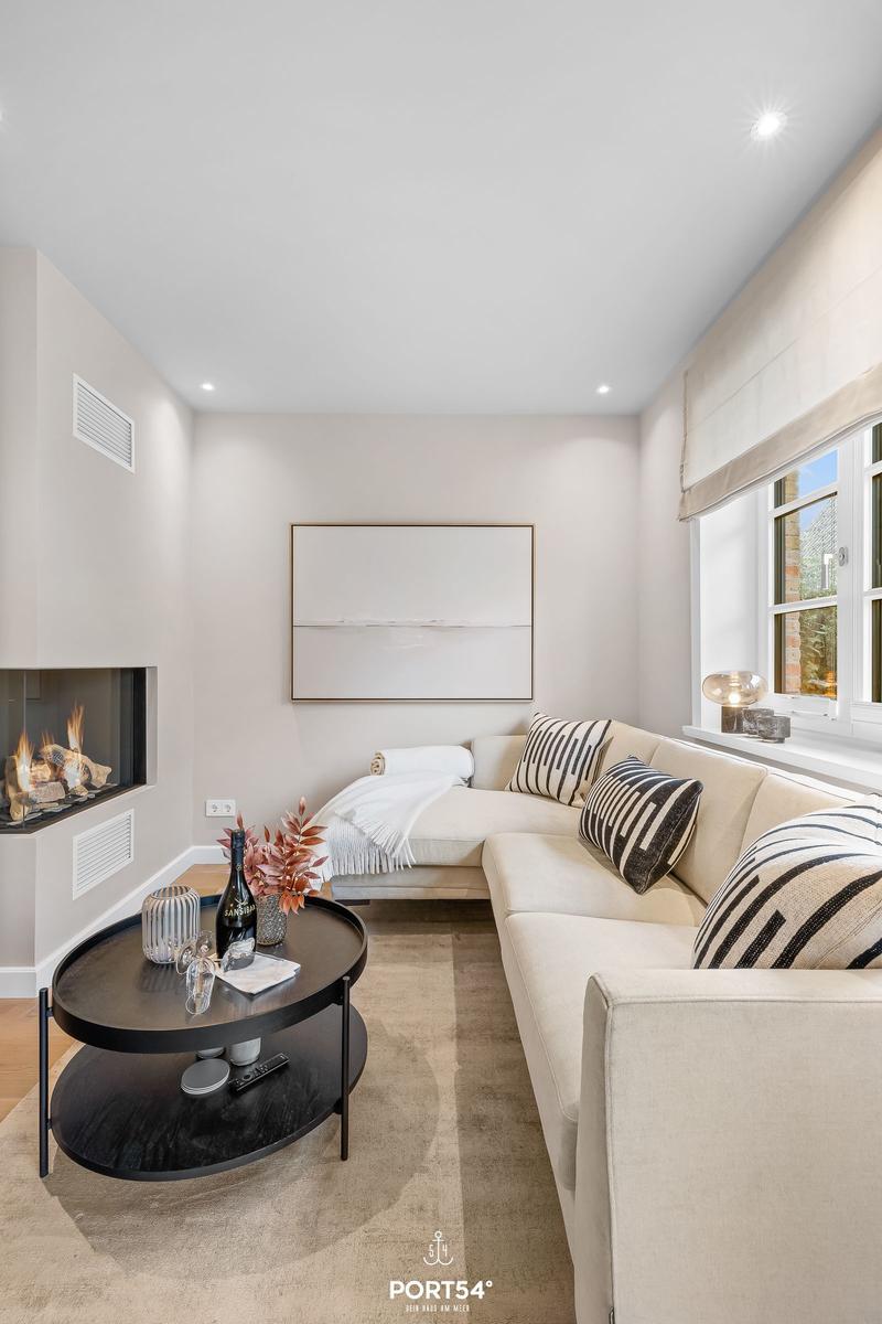 Wohnzimmer mit Ecksofa, Kamin und runden Tisch.