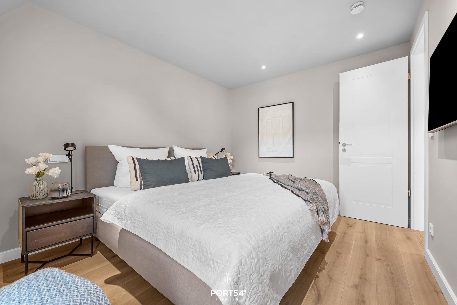 Schlafzimmer mit Bett, Nachttisch und Tür
