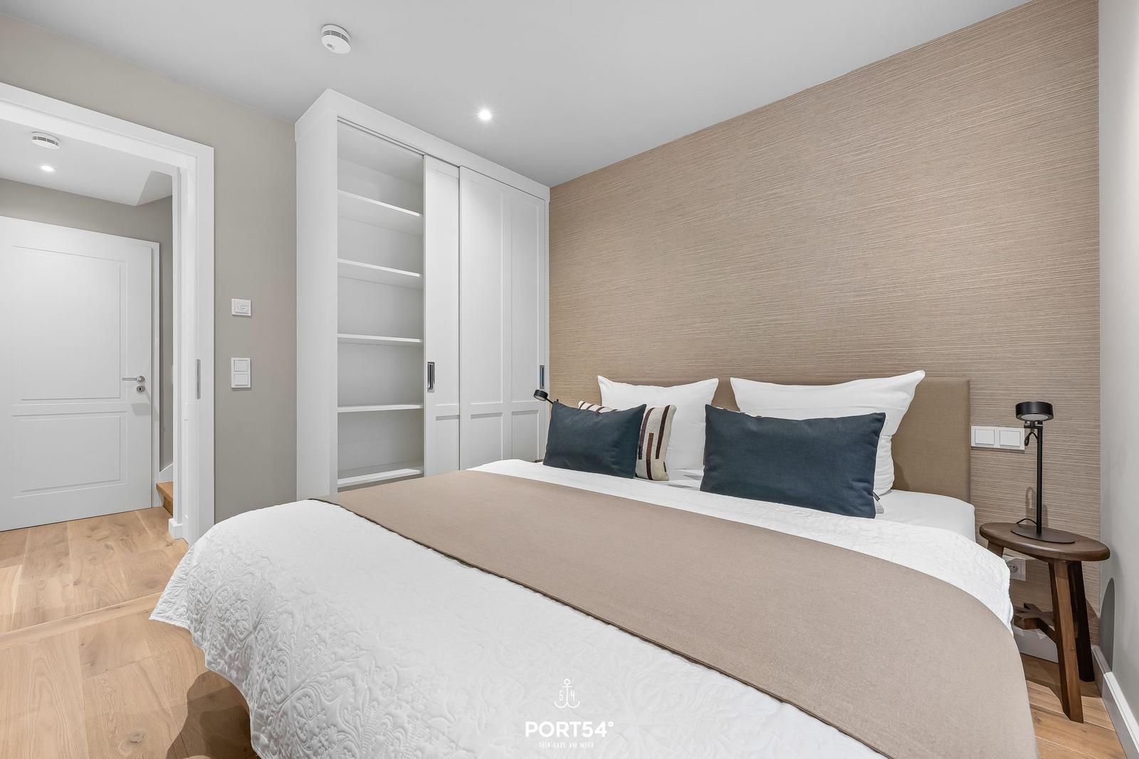 Schlafzimmer mit Bett, Nachttisch und Kleiderschrank.