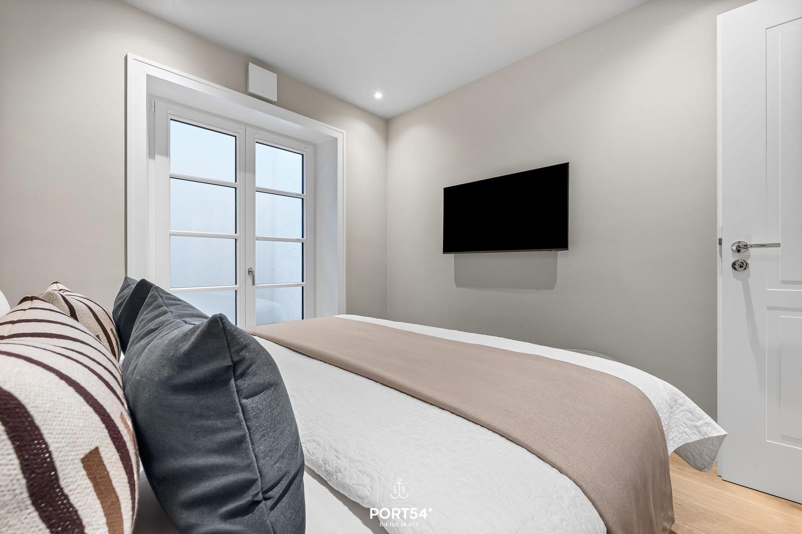 Schlafzimmer mit Bett, TV und Fenster