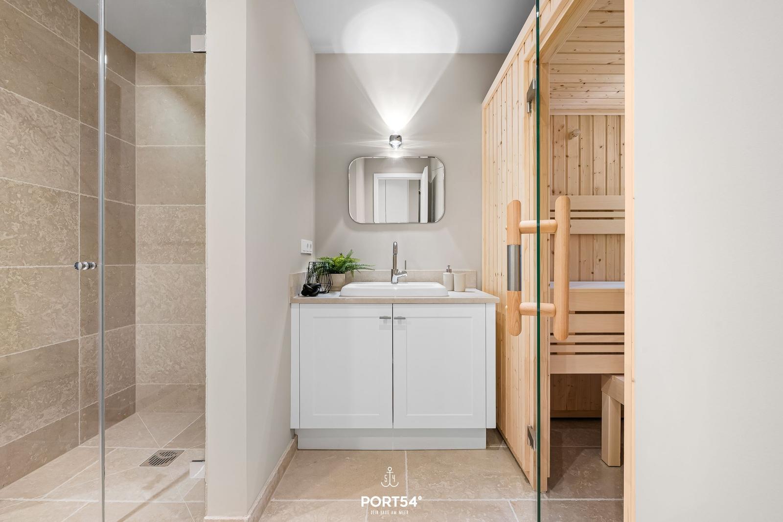 Badezimmer mit Dusche, Waschbecken und Sauna.