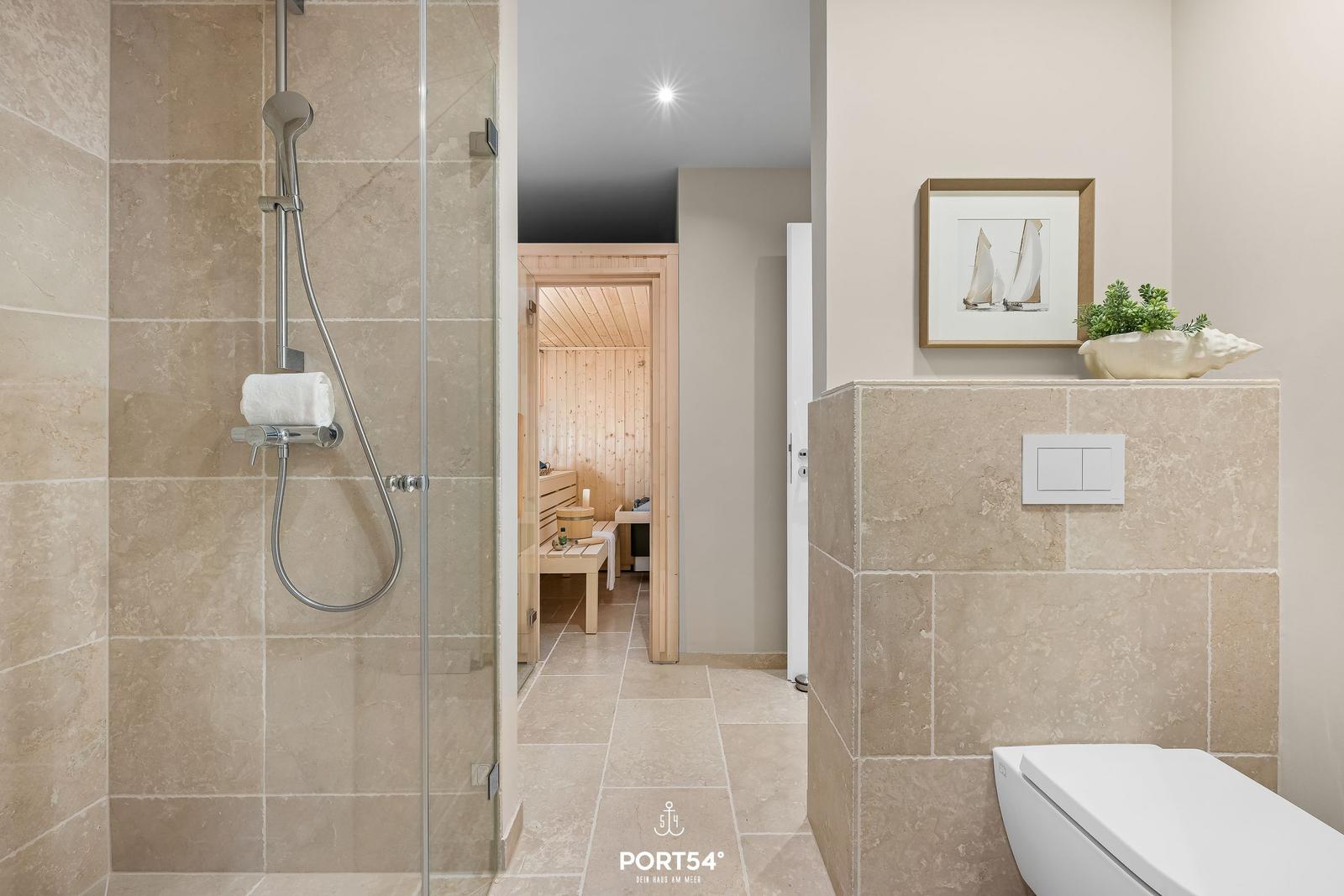 Dusche mit Glaswand, Toilette und Blick in die Sauna.