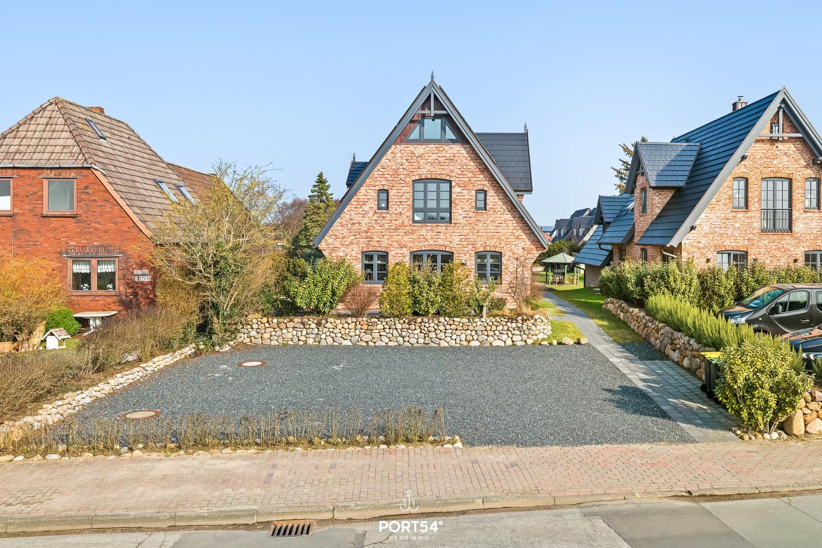 Haus mit Steinmauer und Kiesfläche vorne