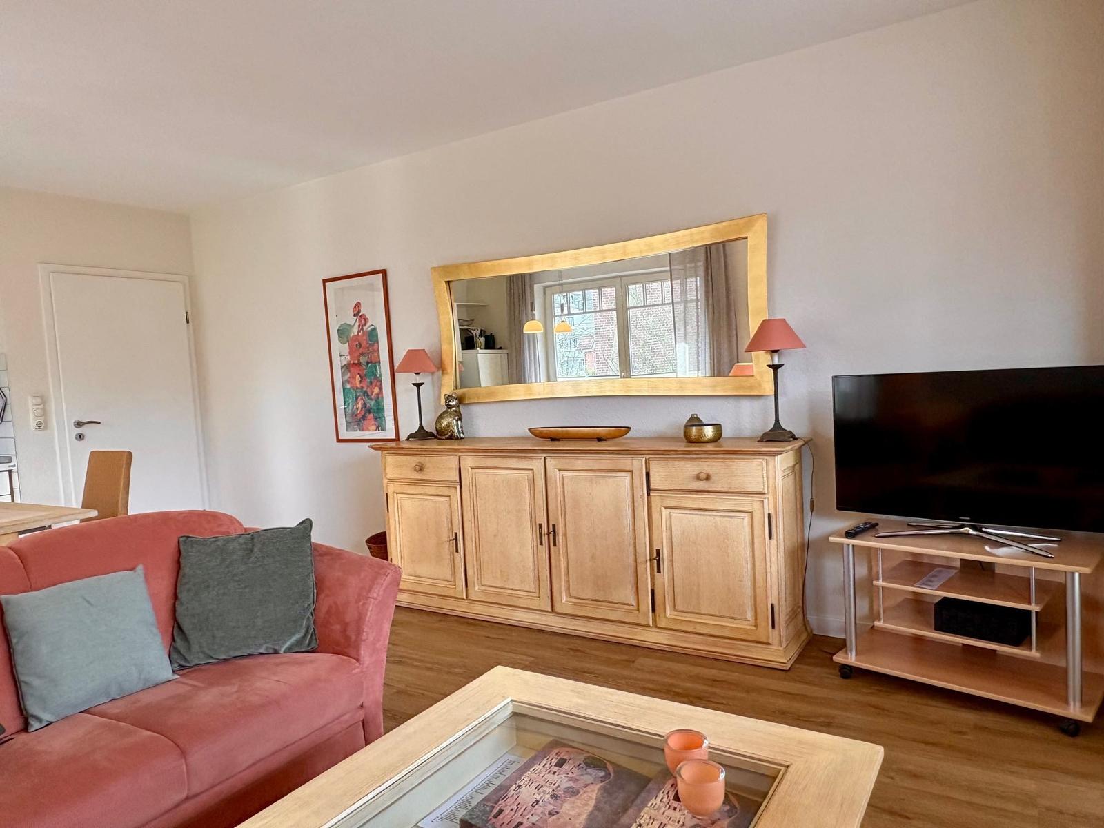 Ein Wohnzimmer mit rotem Sofa, Holzmöbeln und Fernseher.