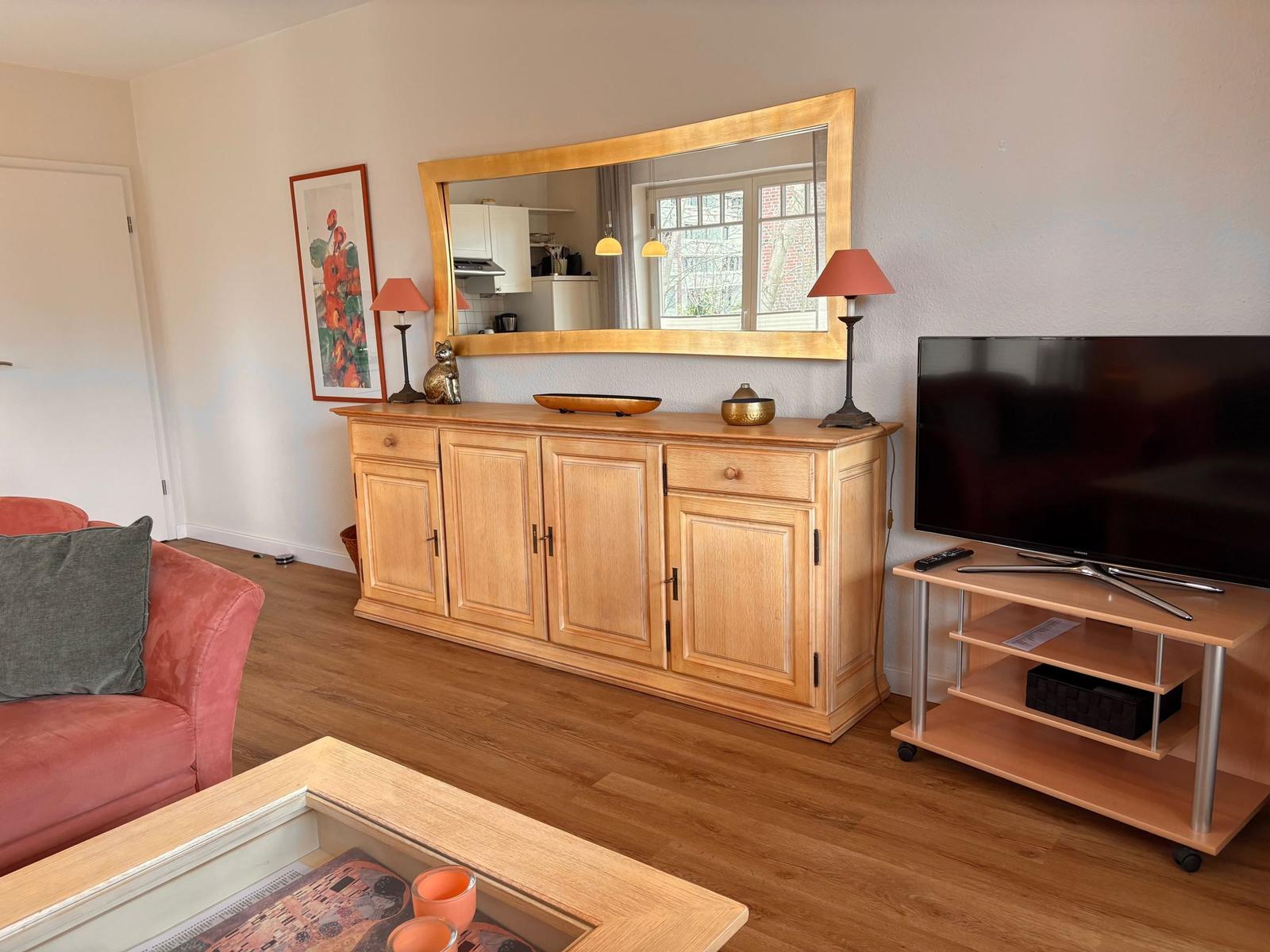 Ein Wohnzimmer mit Holzmöbeln, Fernseher und Spiegel an der Wand.