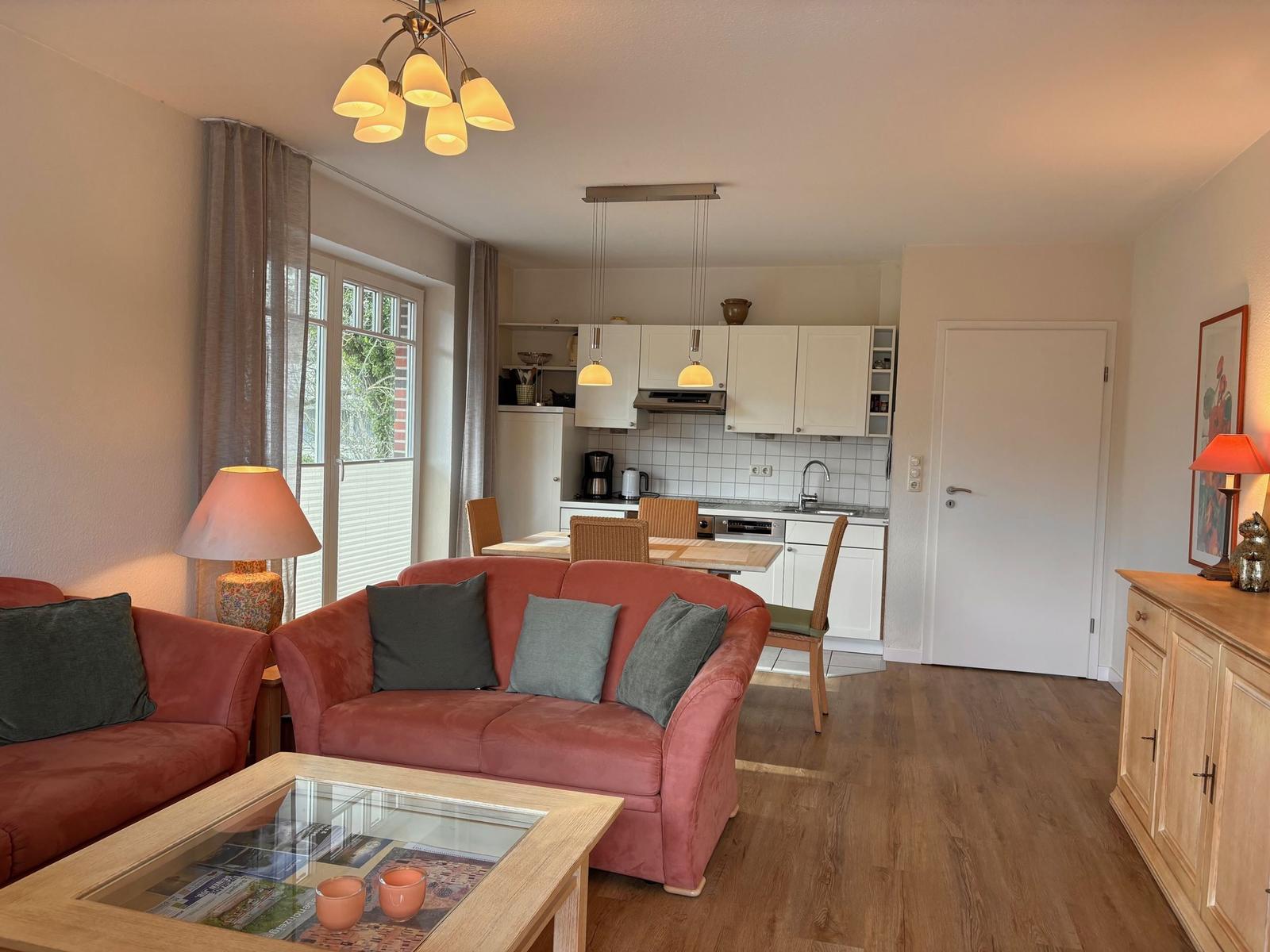 Wohnbereich mit rotem Sofa, Küchenbereich und Holzboden.