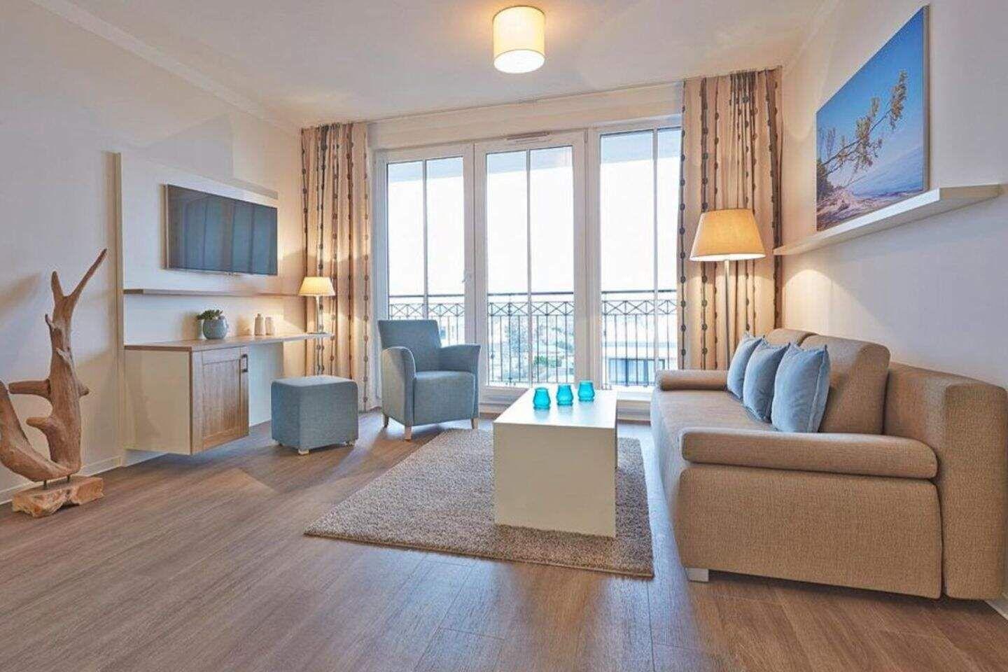 Wohnzimmer mit Sofa, Sessel und Balkonansicht